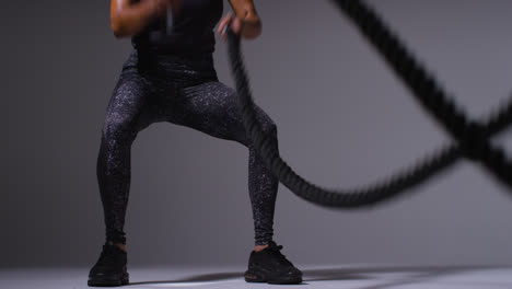 Close-Up-Studio-Shot-Of-Mature-Woman-Wearing-Gym-Fitness-Clothing-Doing-Cardio-Exercise-With-Battle-Ropes-2